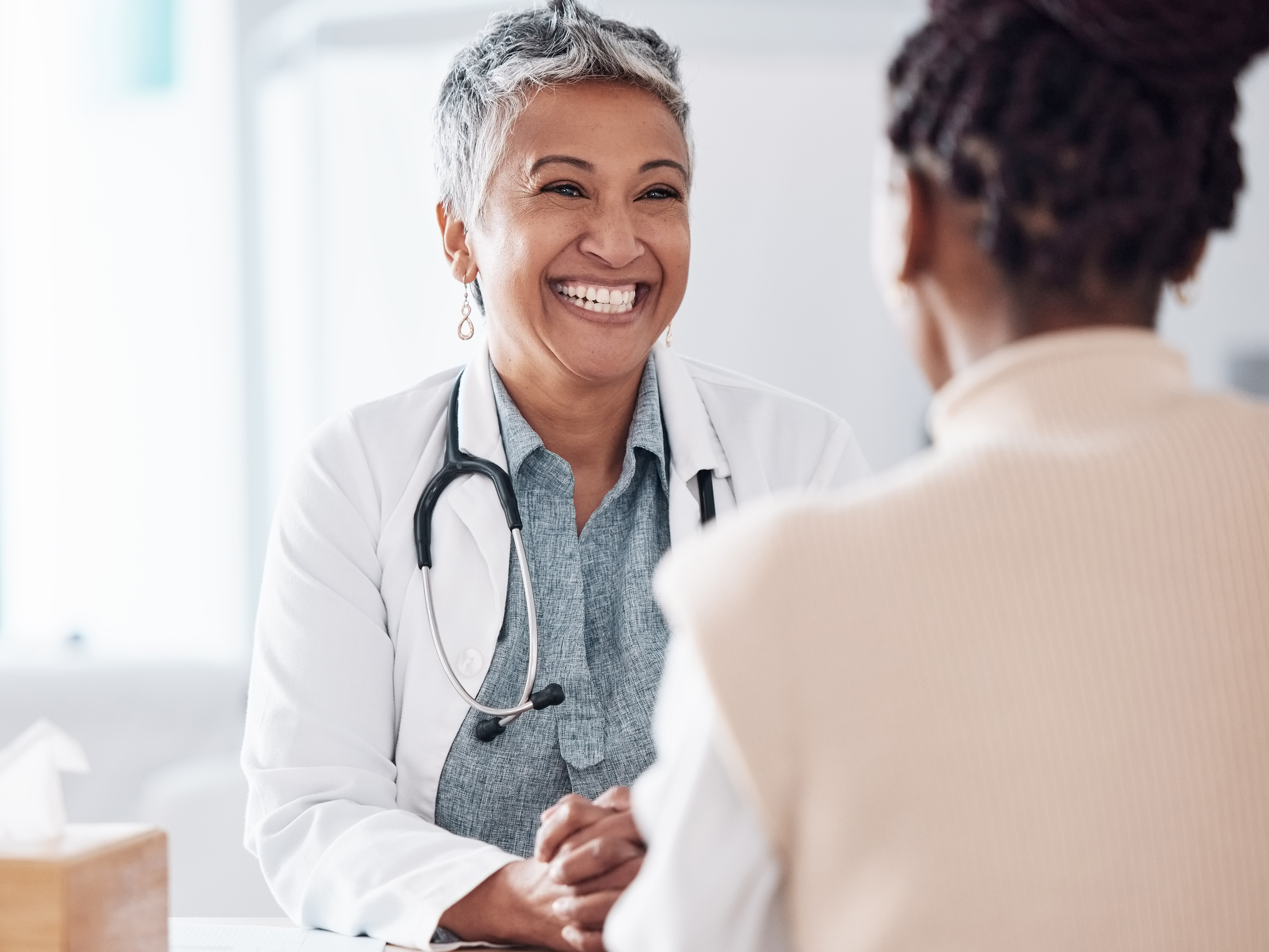 Smiling female doctor sitting at a desk talking with a patient