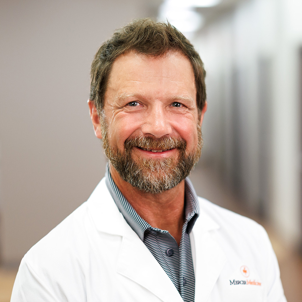Dr. Tim smiling and wearing his white coat in the clinic hallway.